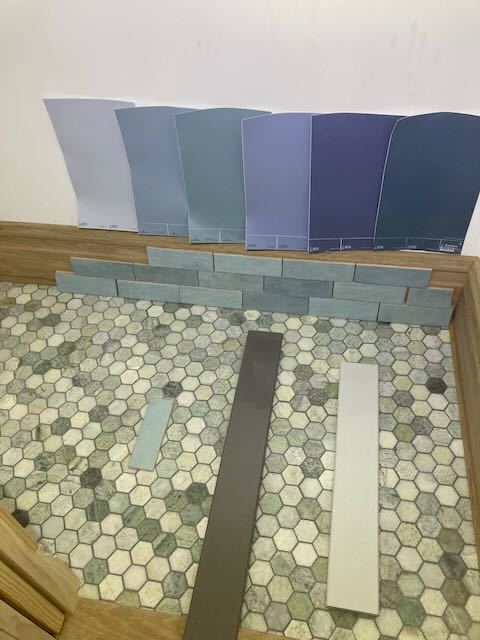 A picture of a mosaic tile floor with paint samples and threshold samples